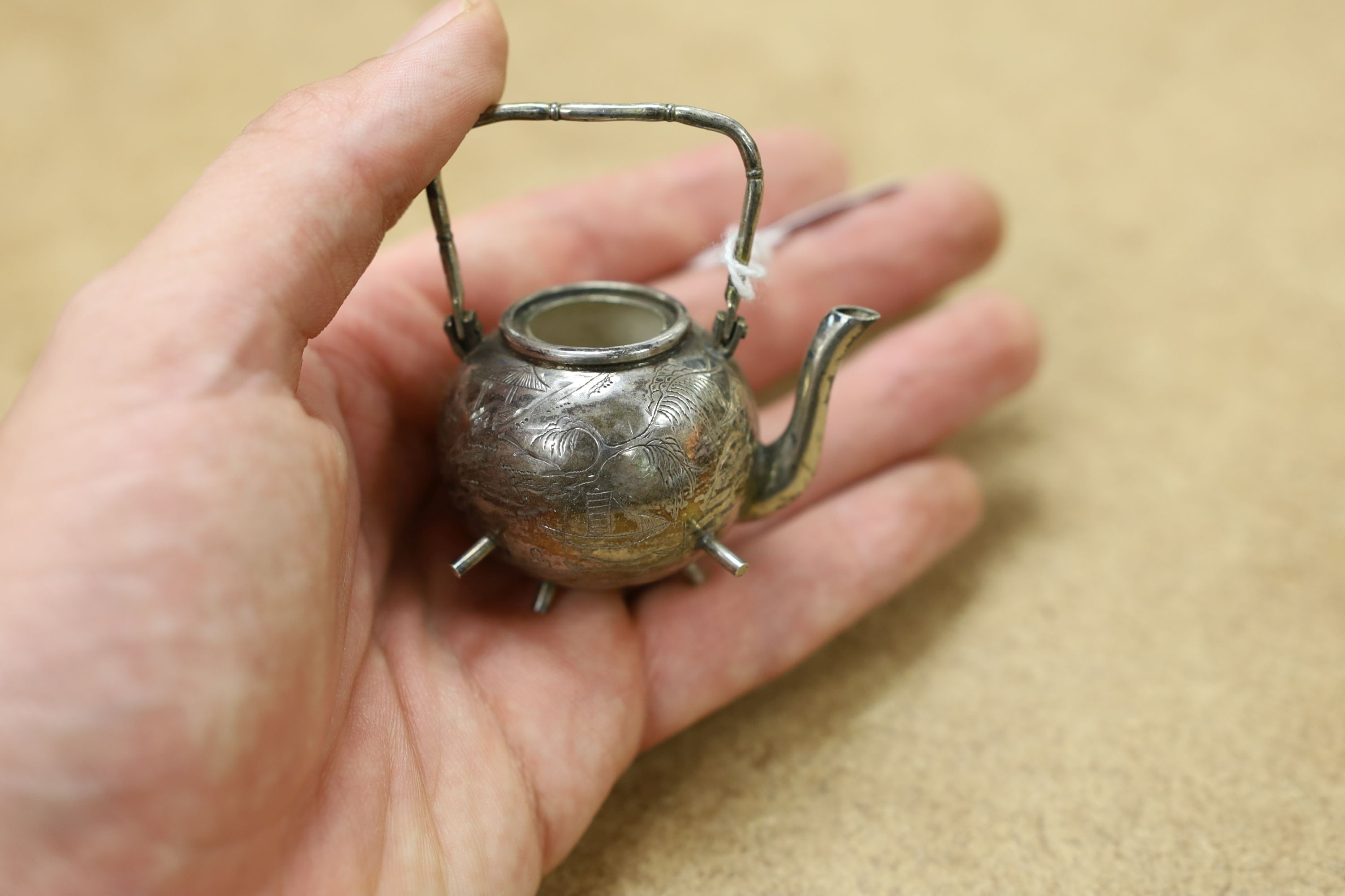Six assorted miniature white metal items including a Chinese tea kettle on stand (lacking lid), height 93mm, maker CS, a similar rickshaw with driver, maker CH, a Chinese condiment and three other items.